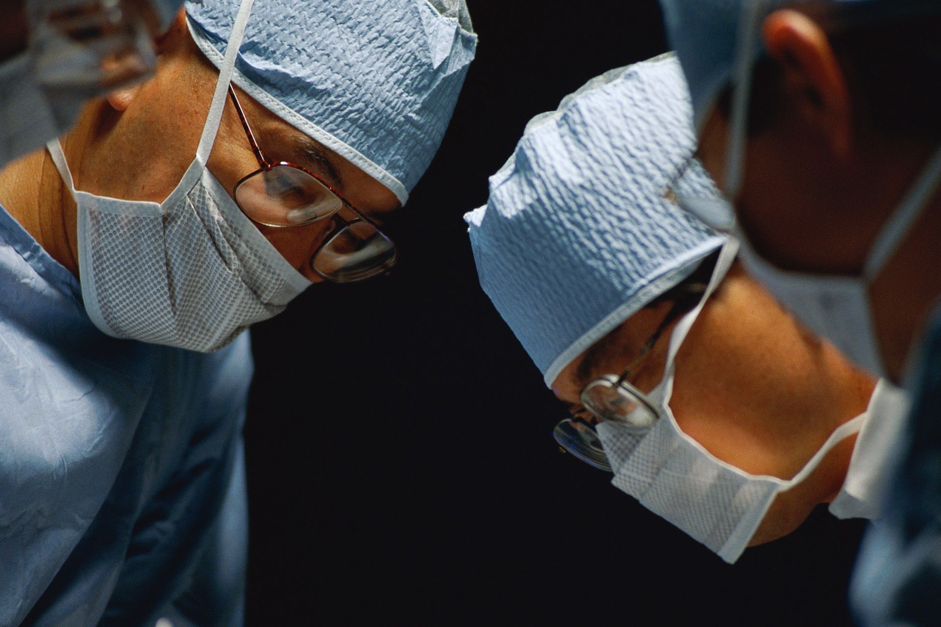 Surgical team performing operation; healthcare; indoors; doctor; surgeon; surgery; caucasian; asian; indian; hospital; mature adults;